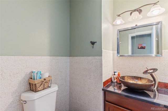 bathroom featuring vanity, tile walls, toilet, and wainscoting