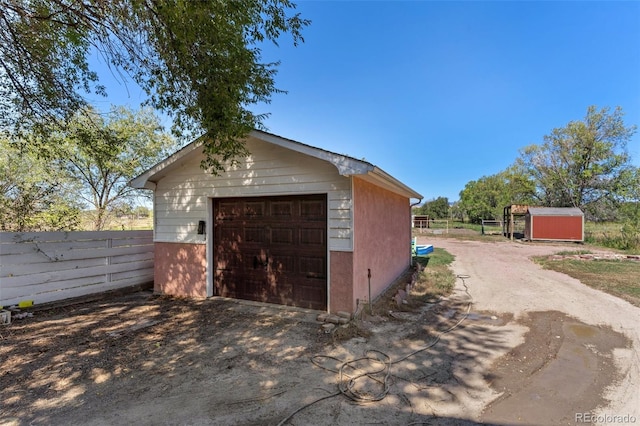 detached garage with fence and driveway