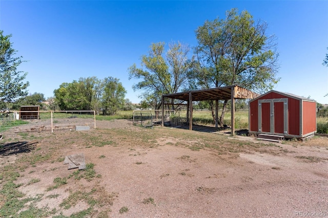 view of yard featuring a storage unit, a detached carport, an outdoor structure, and driveway