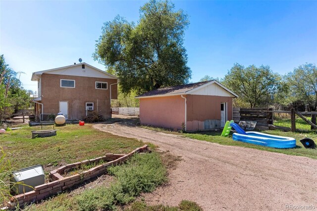 view of side of property with an outdoor structure, a yard, fence, and driveway