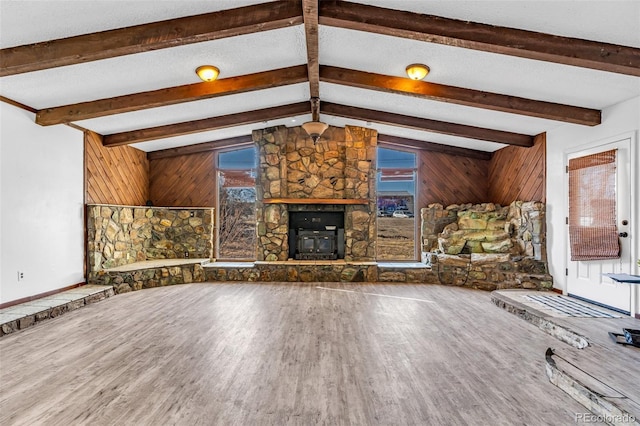 unfurnished living room featuring vaulted ceiling with beams, wooden walls, a textured ceiling, and wood finished floors