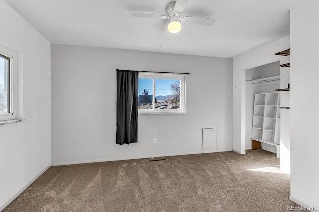 unfurnished bedroom featuring baseboards, carpet flooring, a ceiling fan, and visible vents