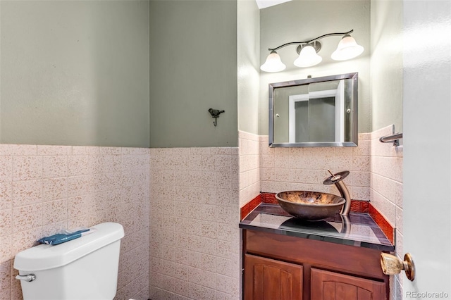 bathroom featuring tile walls, a wainscoted wall, toilet, and vanity