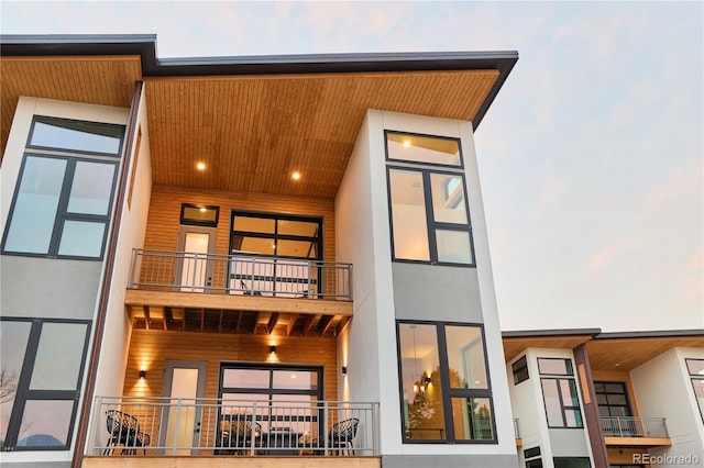 back of property with stucco siding and a balcony