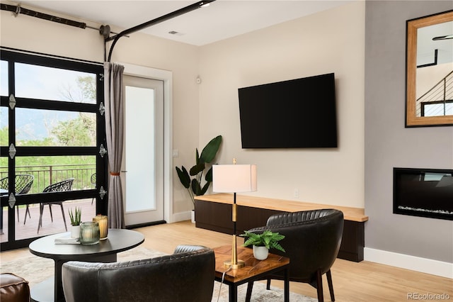 living area with light wood-type flooring and baseboards