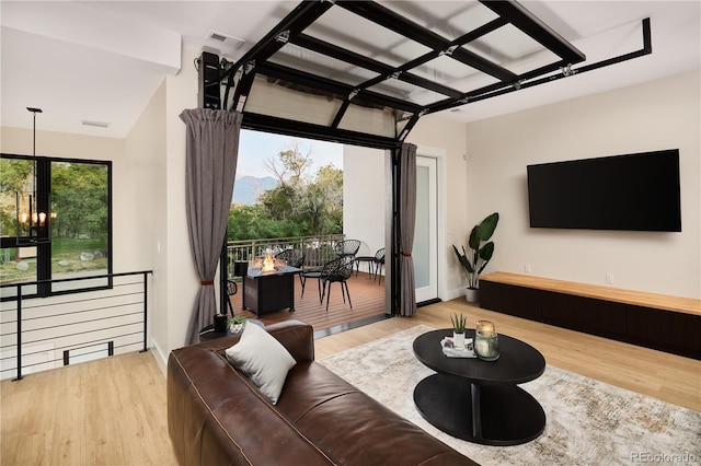 living area with a notable chandelier, visible vents, baseboards, and wood finished floors