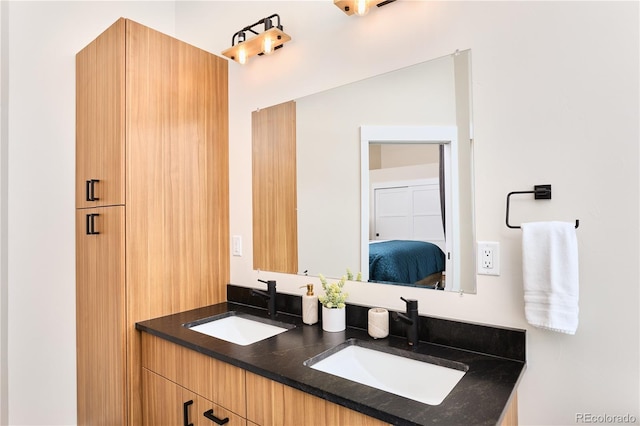 bathroom featuring double vanity, connected bathroom, and a sink