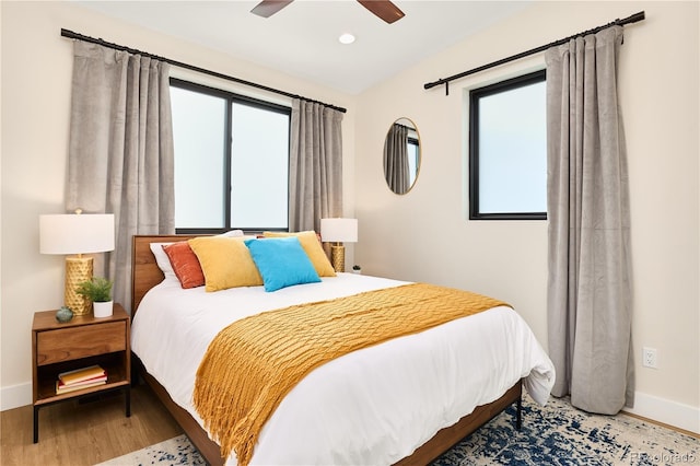 bedroom with multiple windows, baseboards, and wood finished floors