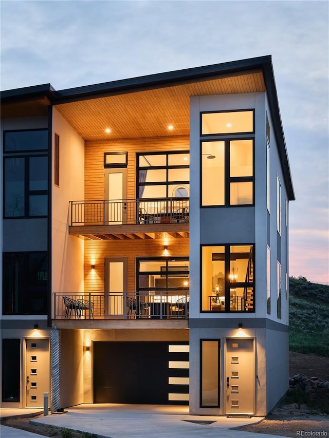 view of front facade featuring a balcony, an attached garage, and stucco siding