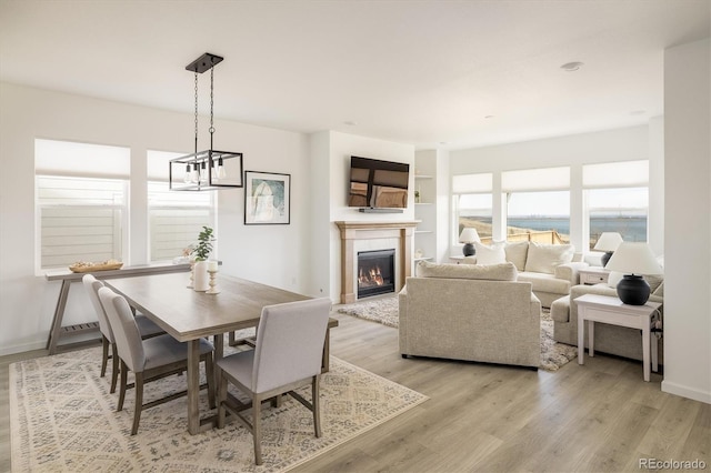 16568 W 92nd Pl, Arvada, CO 80007 - dining space featuring a glass covered fireplace, light wood-type flooring, and a chandelier
