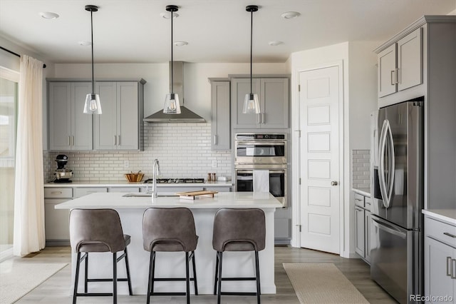 16568 W 92nd Pl, Arvada, CO 80007 - kitchen featuring stainless steel appliances, gray cabinets, wall chimney range hood, and a kitchen bar