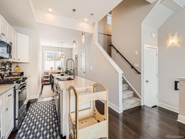 kitchen featuring dark wood-style flooring, light countertops, a sink, stainless steel appliances, and backsplash