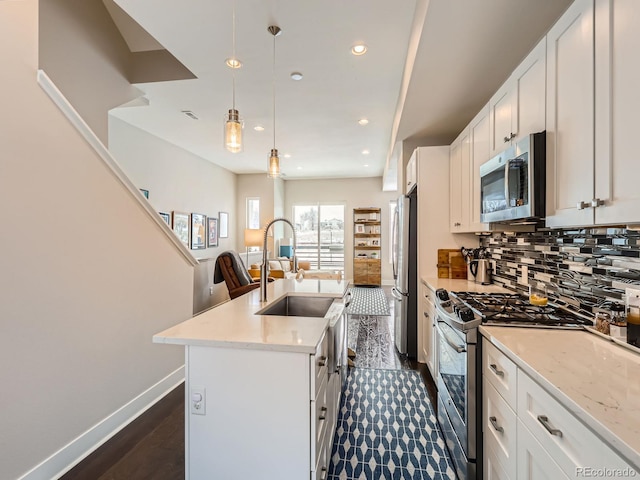 kitchen featuring tasteful backsplash, hanging light fixtures, appliances with stainless steel finishes, an island with sink, and recessed lighting