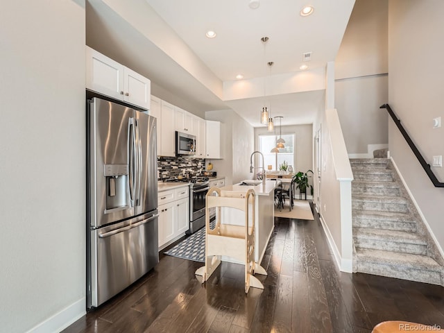 kitchen with white cabinets, dark wood-style floors, a center island with sink, backsplash, and stainless steel appliances