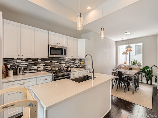 kitchen featuring decorative light fixtures, dark wood-style flooring, white cabinetry, stainless steel appliances, and backsplash