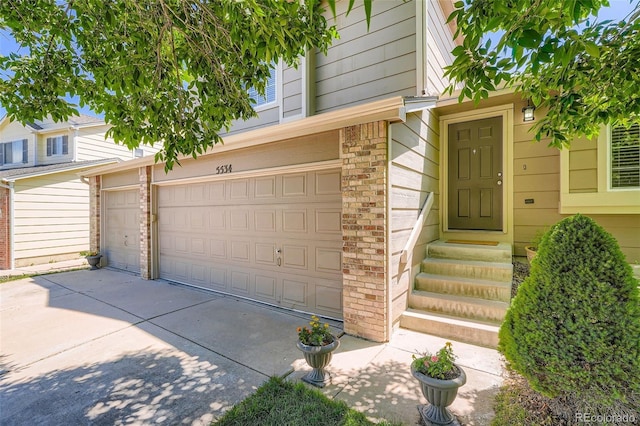 5534 S Wenatchee St, Aurora, CO 80015 - view of exterior entry with brick siding, concrete driveway, and an attached garage