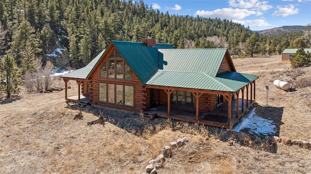 2555 New Mill Gulch Rd, Canon City, CO 81212 - rear view of property with log siding, a chimney, a wooded view, metal roof, and a mountain view