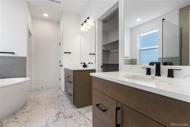 5621 W 141st Ln, Broomfield, CO 80020 - bathroom featuring two vanities, marble finish floors, a freestanding bath, recessed lighting, and a walk in closet
