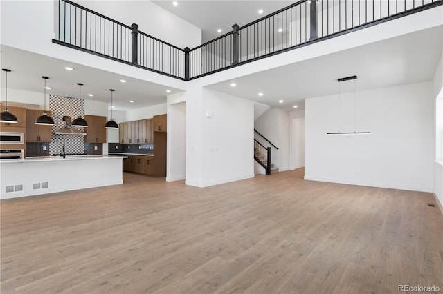 5621 W 141st Ln, Broomfield, CO 80020 - unfurnished living room featuring a high ceiling, light wood finished floors, recessed lighting, and stairs