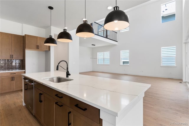 5621 W 141st Ln, Broomfield, CO 80020 - kitchen featuring light wood-type flooring, a high ceiling, open floor plan, an island with sink, and light stone counters