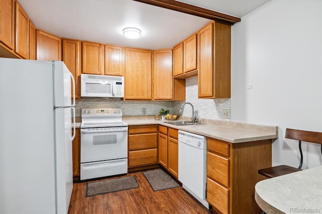 kitchen with dark wood-style flooring, light countertops, backsplash, a sink, and white appliances