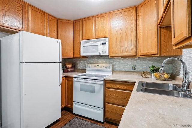 kitchen featuring white appliances, light countertops, a sink, dark wood finished floors, and backsplash