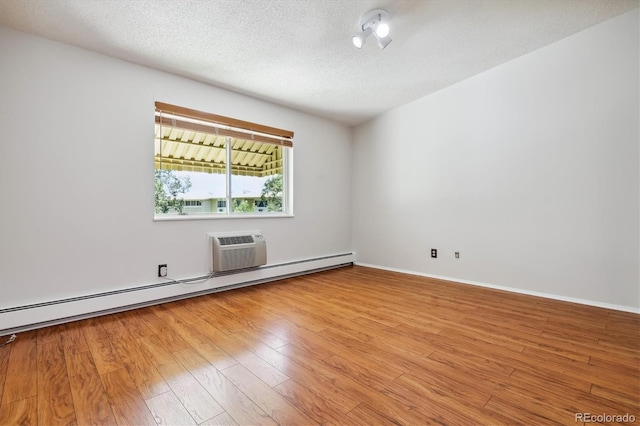 spare room with wood finished floors, baseboards, a textured ceiling, and a baseboard heating unit
