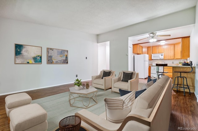 living area featuring baseboards, a ceiling fan, and dark wood-style floors