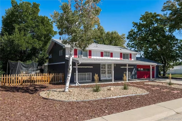 traditional home featuring fence, driveway, french doors, a garage, and a trampoline