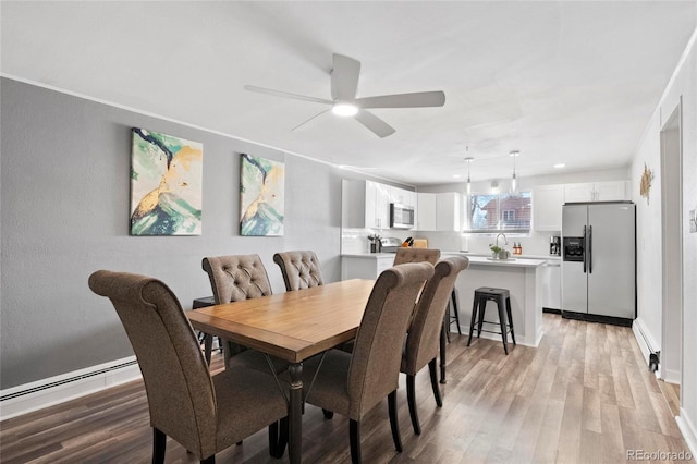 dining room with light wood-style flooring, baseboard heating, and ceiling fan