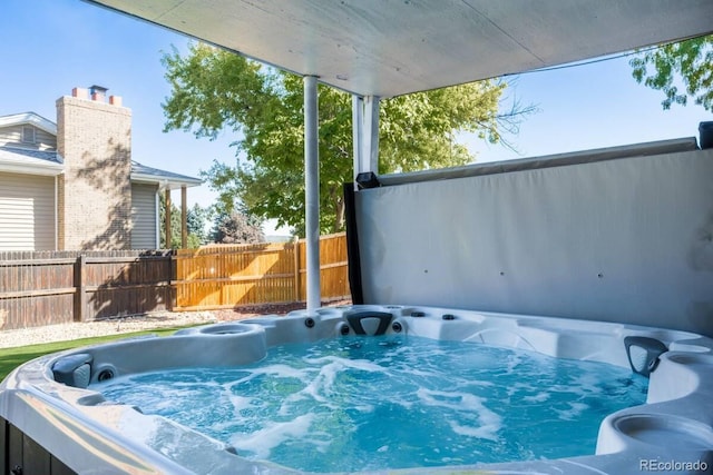 view of swimming pool with fence and a hot tub