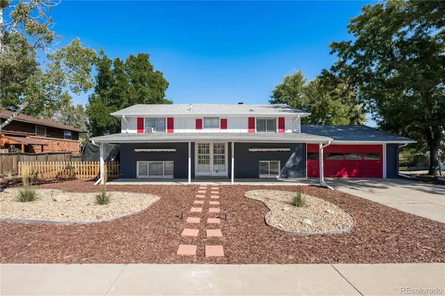 traditional-style house with french doors, a garage, driveway, and fence