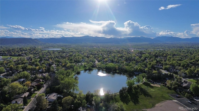 aerial view with a water and mountain view and a wooded view