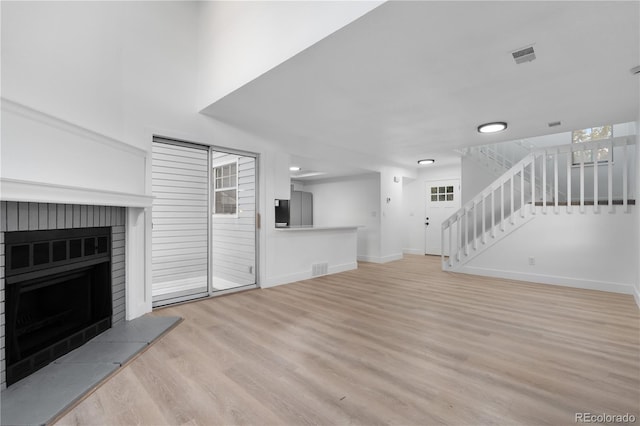 12635 E Pacific Cir Unit A, Aurora, CO 80014 - unfurnished living room featuring wood finished floors, stairway, a brick fireplace, baseboards, and healthy amount of natural light