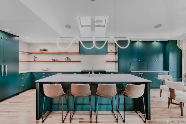 kitchen with built in fridge, an island with sink, and light hardwood / wood-style flooring