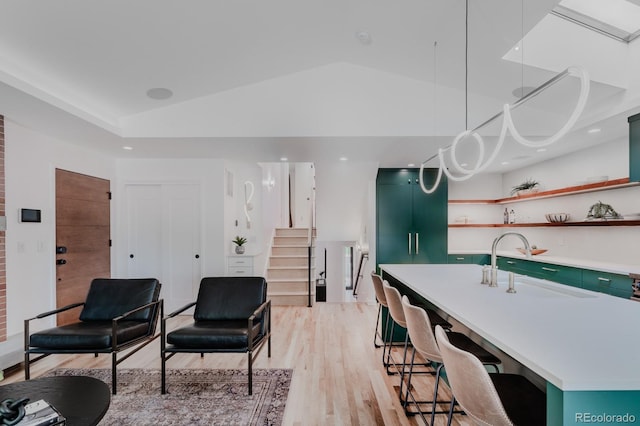 interior space with green cabinets, lofted ceiling, sink, and an island with sink