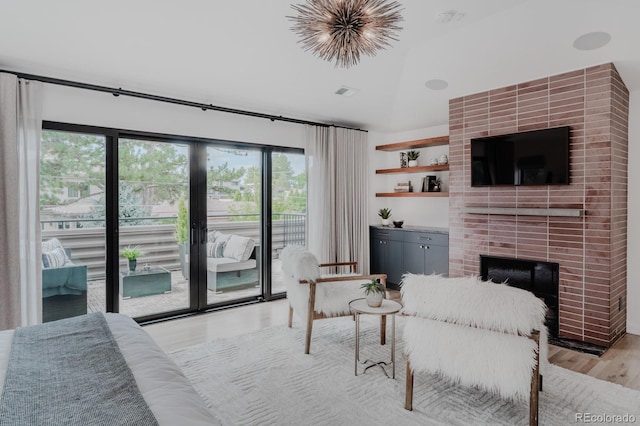 living room with a brick fireplace, lofted ceiling, and light hardwood / wood-style floors