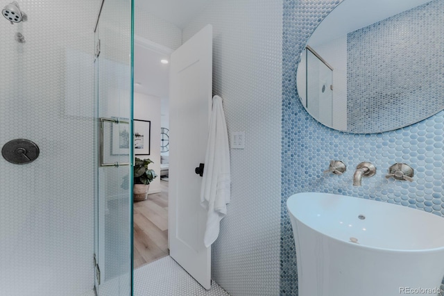 bathroom with a shower, wood-type flooring, sink, and tile walls