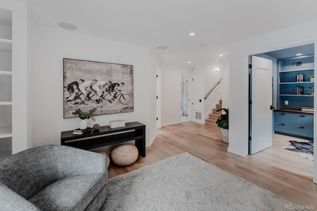 sitting room with built in shelves and wood-type flooring