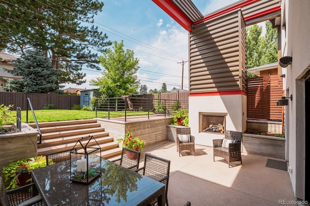 view of patio featuring exterior fireplace and a shed