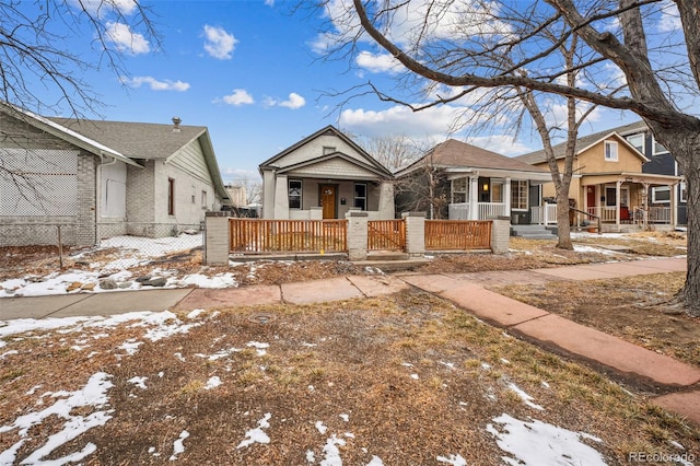 bungalow-style home with a fenced front yard and covered porch