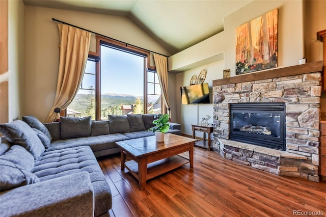 living room featuring a stone fireplace, vaulted ceiling, and dark wood-type flooring