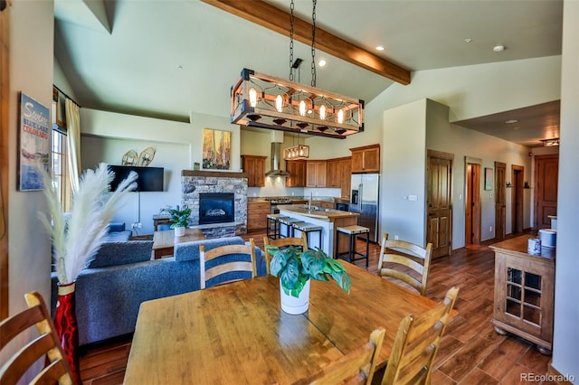 dining space with dark wood-type flooring, sink, beam ceiling, a fireplace, and high vaulted ceiling