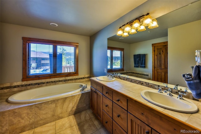 bathroom featuring tile patterned flooring, tiled bath, and vanity