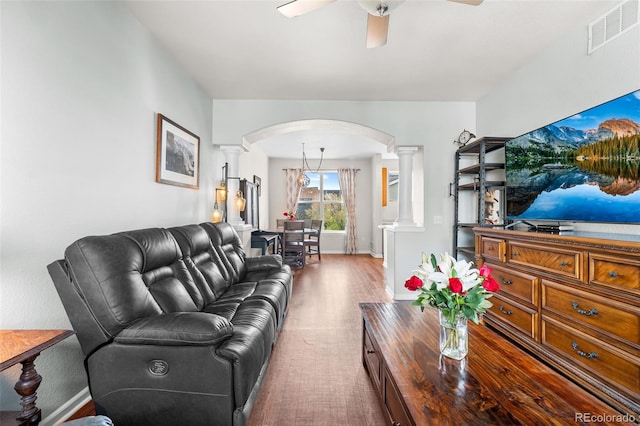 living room featuring ceiling fan, arched walkways, baseboards, decorative columns, and visible vents