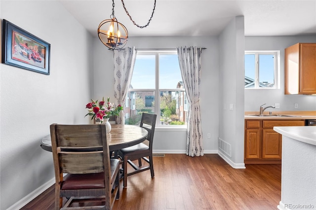dining space with visible vents, baseboards, wood finished floors, and a notable chandelier