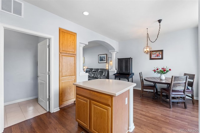 kitchen featuring visible vents, arched walkways, light countertops, baseboards, and ornate columns