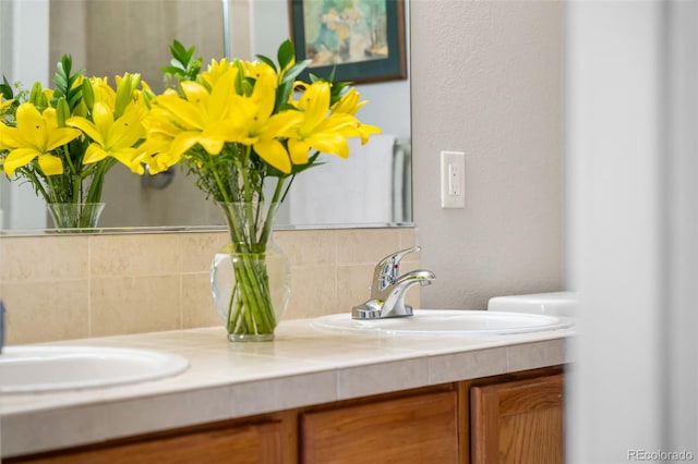 bathroom with double vanity, a sink, and tasteful backsplash