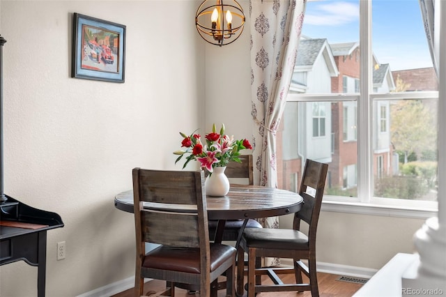 dining space with baseboards, a chandelier, wood finished floors, and a healthy amount of sunlight