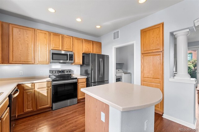 kitchen with stainless steel appliances, recessed lighting, wood finished floors, ornate columns, and washing machine and dryer